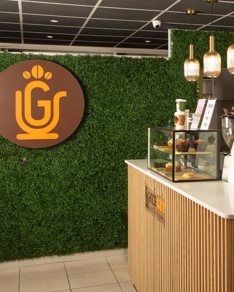 Inside Grande Cafe: the logo on the living green wall, pendant lights and the pastry counter